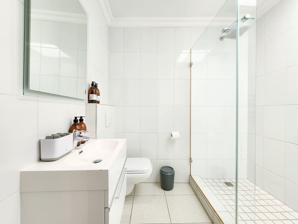 A modern bathroom with a white sink, toilet, and glass-enclosed shower.