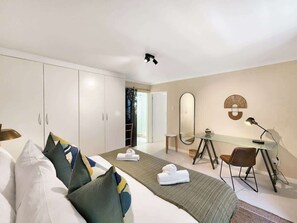 Ein Hotelzimmer mit Bett, Schreibtisch, Stuhl, Spiegel und Kleiderschrank.