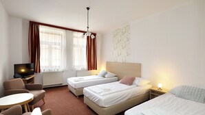 A hotel room with two single beds, a sofa, a TV, and a small table. - Pension U Tří sedláků (České Budějovice)