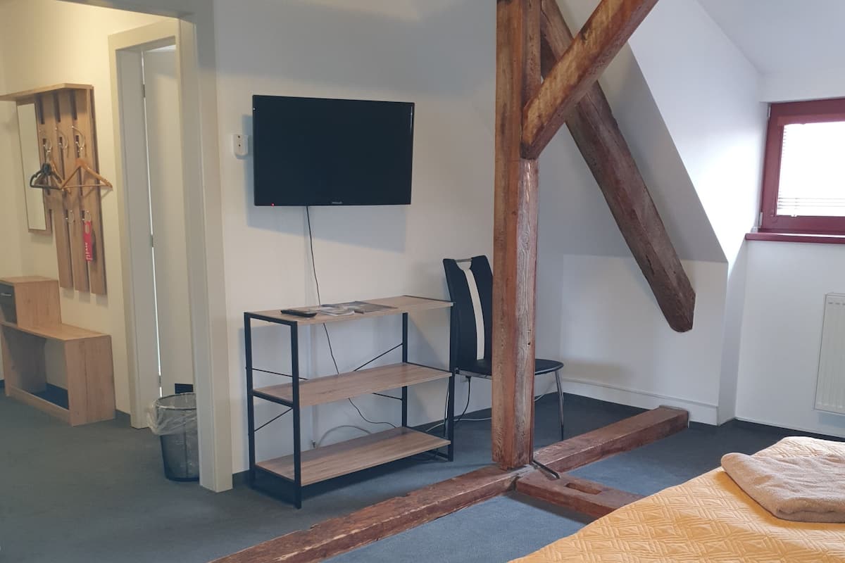 A room with a bed, a desk, a chair, a TV, and a window.