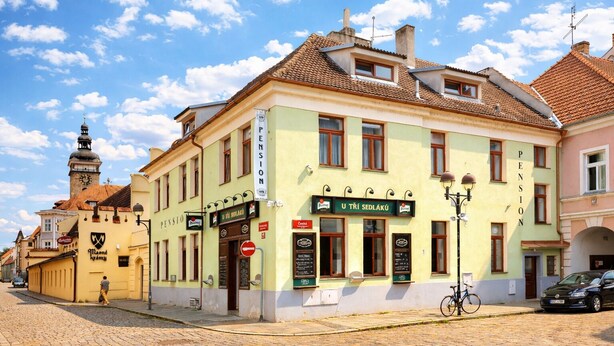A building with a sign 'U TRI SEDLÁKÚ' and a bicycle parked outside. - Pension U Tří sedláků (České Budějovice)