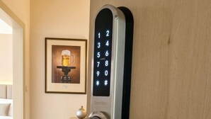 A modern hotel room with a digital keypad lock, a framed picture on the wall, and a small trash bin. - Pension U Tří sedláků (České Budějovice)