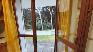 Ein Zimmer mit einer Schiebetür zu einem Balkon mit Blick auf Bäume und eine gepflasterte Fläche.