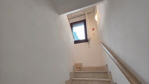 Eine Treppe mit Handlauf, ein Fenster mit Aussicht und ein Rauchmelder an der Wand.