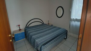 Une chambre à coucher avec un lit, une commode, un miroir et une porte.