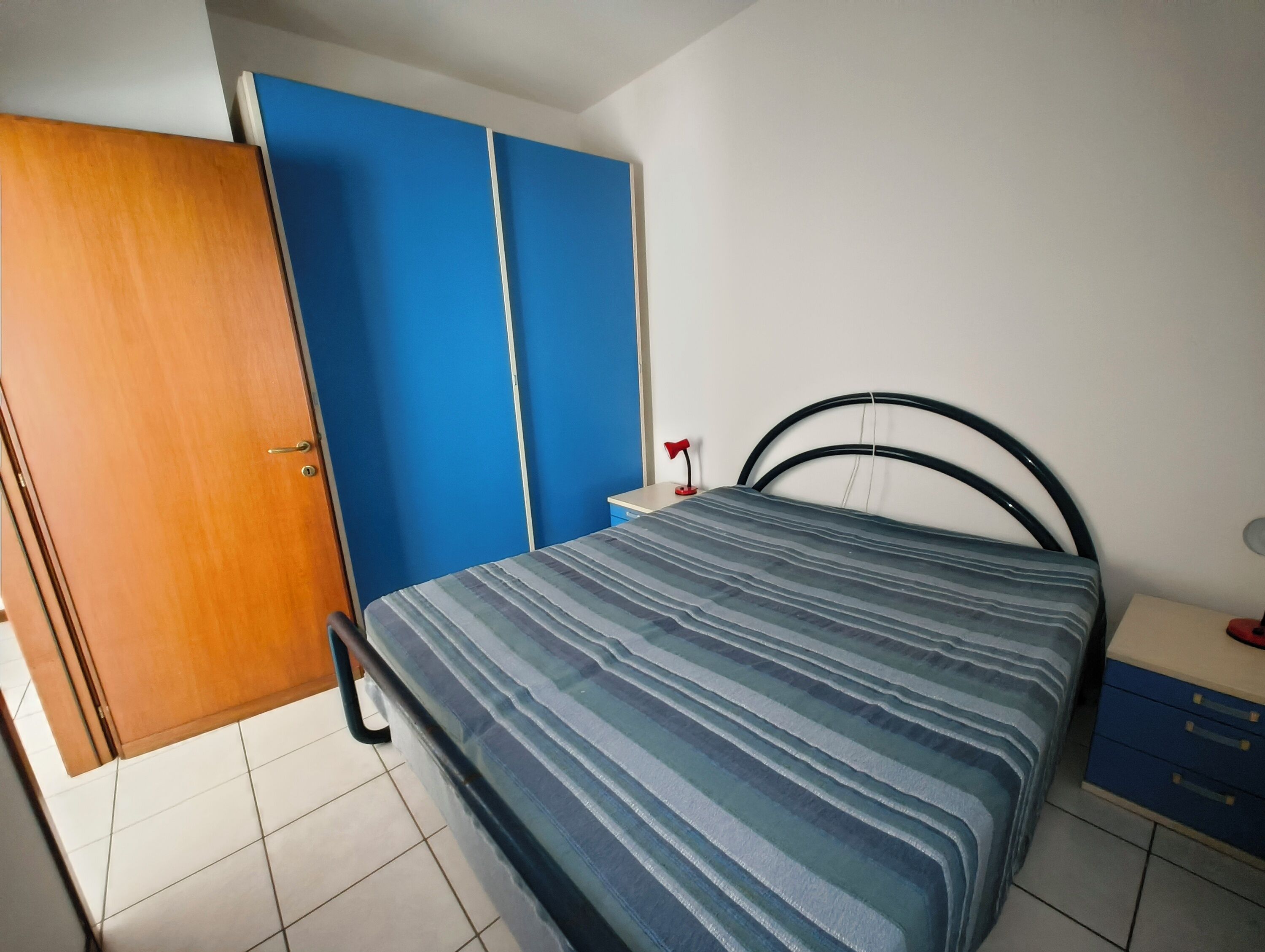 A bedroom with a bed, a wardrobe, and a nightstand.