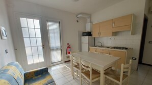 Une cuisine compacte comprenant une table à manger, des chaises, un four à micro-ondes et une cuisinière à gaz.