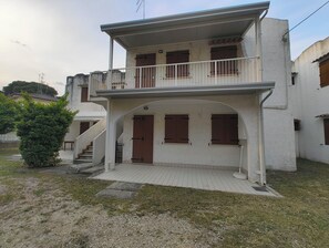 A two-story building with a balcony, a staircase, and a small garden area.