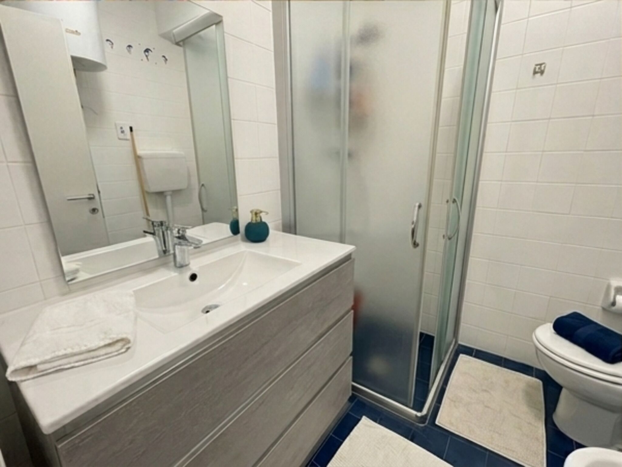 A bathroom with a white sink, mirror, and glass shower enclosure.