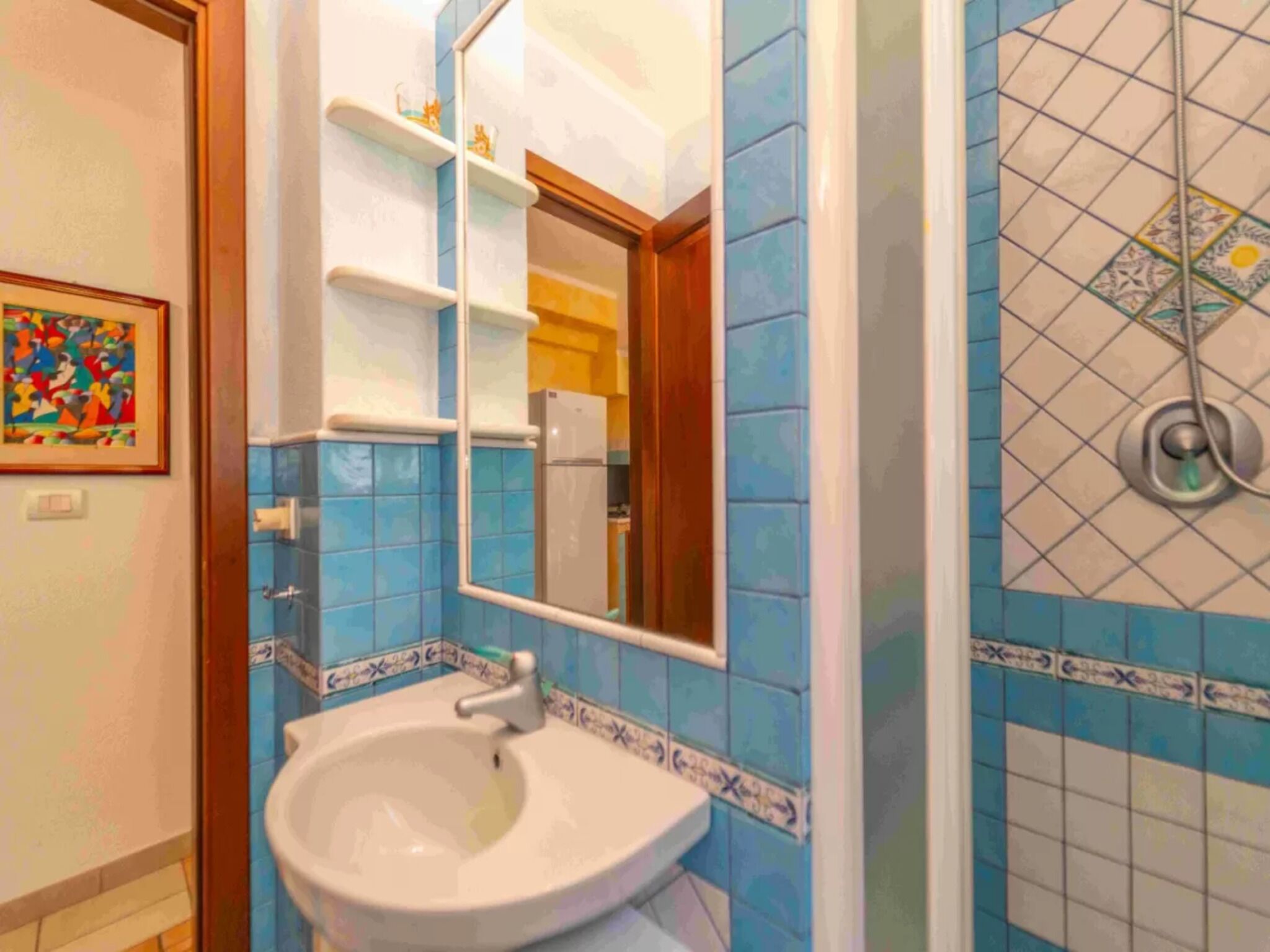 A bathroom with a sink, mirror, and blue tiled walls.
