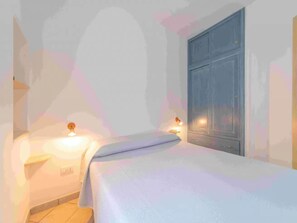 Une chambre à coucher avec un lit, des lampes de chevet et une armoire.