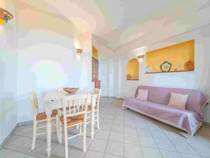 Un espace repas comprenant une table et des chaises, un canapé et un mur agrémenté d’objets décoratifs.
