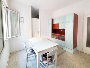 A room with a white table, two chairs, a wardrobe, and a door. - Spacious seafront stay in Jesolo (Lido di Jesolo)