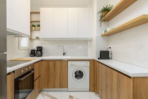 Eine kleine Küche mit Geschirrspüler, Backofen und Kaffeemaschine.