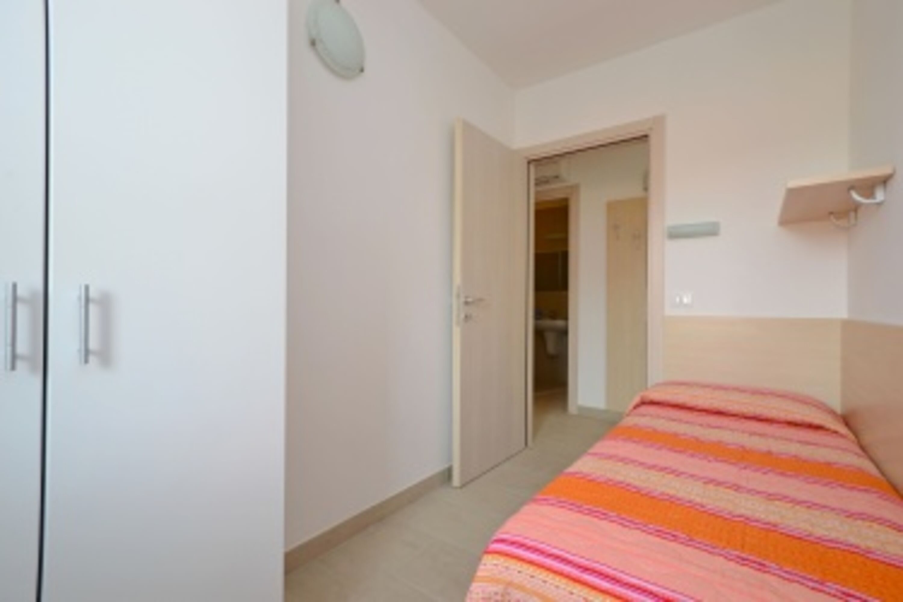 Ein Schlafzimmer mit Bett, Kleiderschrank und einer Tür zu einem Badezimmer.