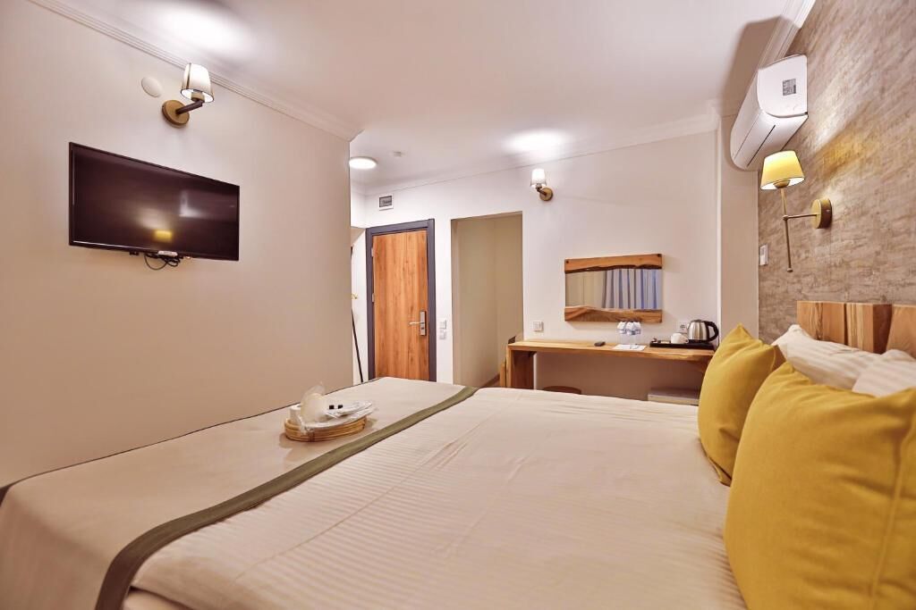 Ein Hotelzimmer mit Bett, Schreibtisch, Flachbildfernseher und Spiegel.