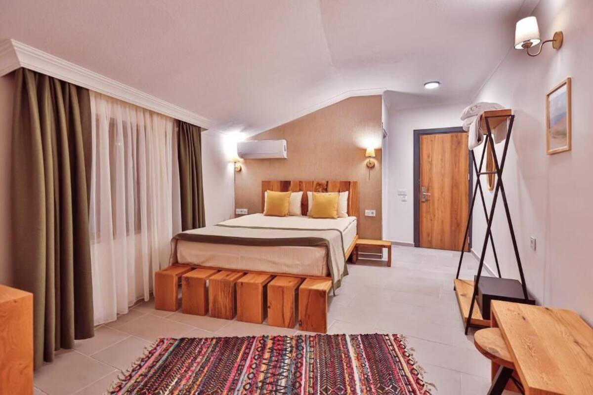 A bedroom with a bed, bedside tables, a bench, a rug, and a wooden door.