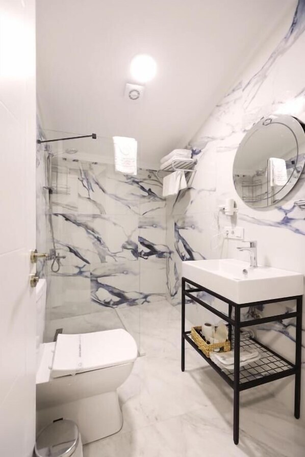 A bathroom with a toilet, sink, and shower.