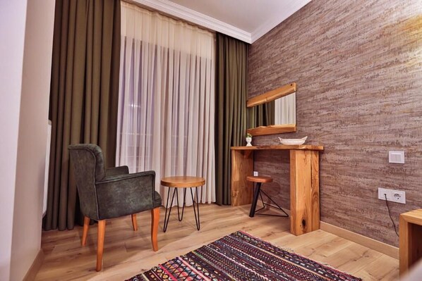 A room with a wooden floor, a chair, a small table, a mirror, and a window with curtains. - Livadi Jur  (Akcakoca)