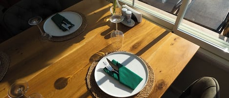 A dining area with tables set for two, a view of a pool outside, and a window overlooking the pool area.