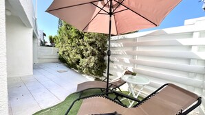 A patio with a table and chairs, a large umbrella, and a white fence. - STAY Heaven Apartment (Ayia Napa)