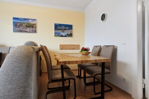 Un'area pranzo con un tavolo di legno, quattro sedie, una panca e due quadri appesi al muro.