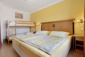 Quarto com uma cama de solteiro, uma cama individual, cabeceira de madeira, luminárias de cabeceira e uma mesa pequena.