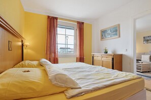Una camera da letto con un letto, una finestra con tende, un comodino, una lampada e un quadro appeso al muro.