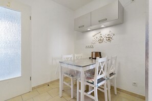 Un espace repas comprenant une table, des chaises, une fenêtre et un meuble fixé au mur.
