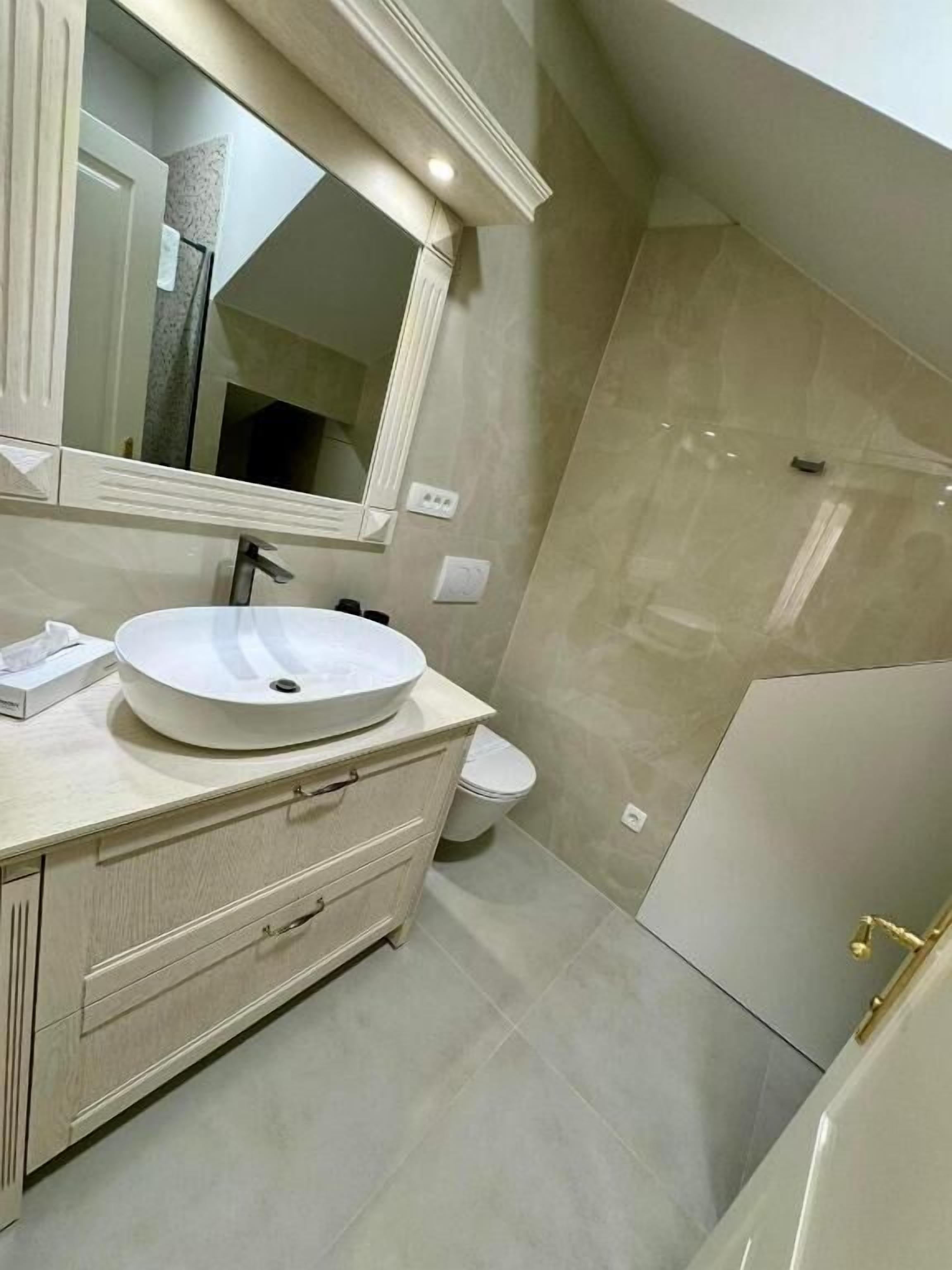 Une salle de bain moderne avec un grand lavabo, un miroir et un espace douche.