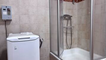 A shower area with a glass enclosure, a white water heater, and a tiled wall with a diamond pattern.