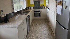 Een compacte keuken met witte kastjes, een roestvrijstalen koelkast en een betegelde vloer.