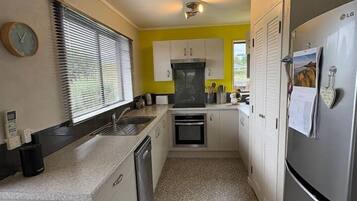 A compact kitchen with white cabinets, a stainless steel refrigerator, and a tiled floor.