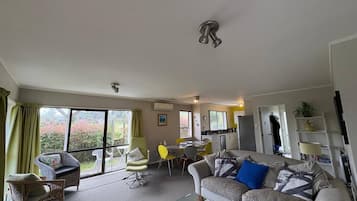 A spacious living room with a sofa, chairs, a dining table, and a kitchen area.