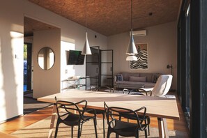 A modern living space with a dining area, a sofa, a TV, and a large mirror.