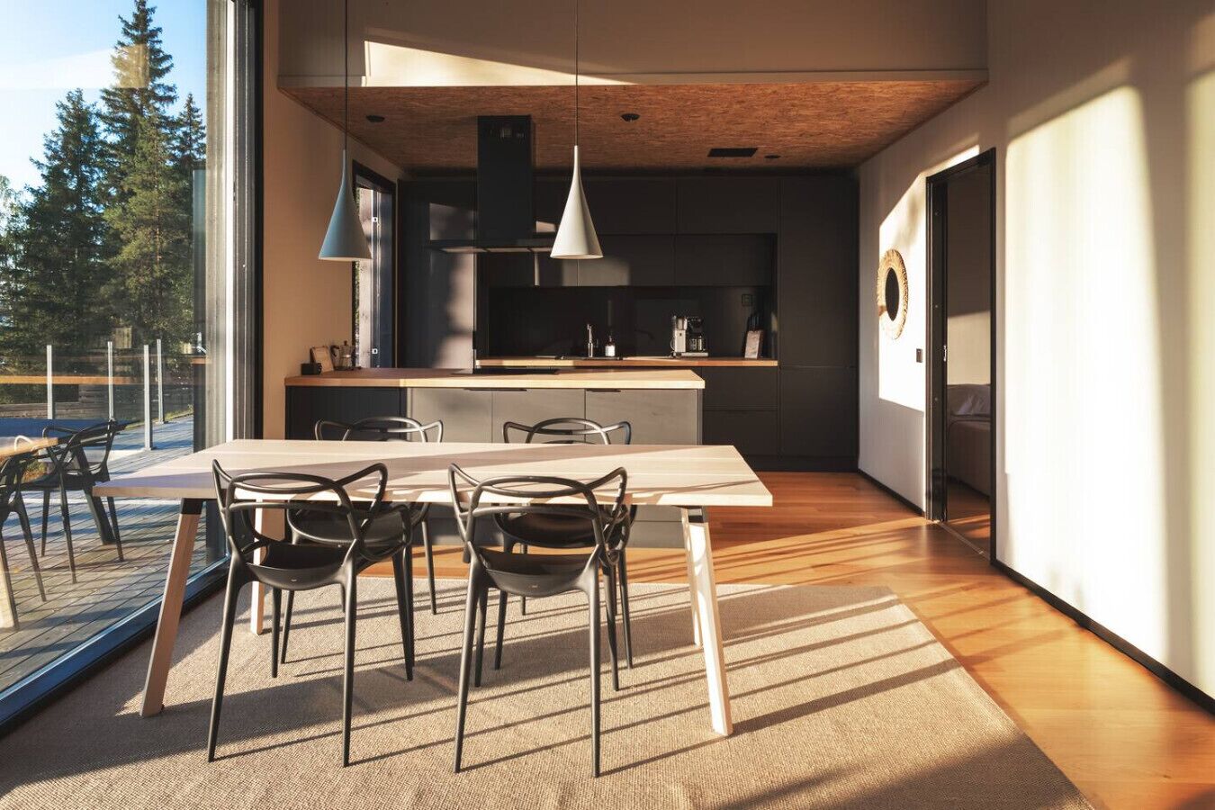 Une cuisine moderne avec un coin repas, de grandes fenêtres et une vue sur les arbres.