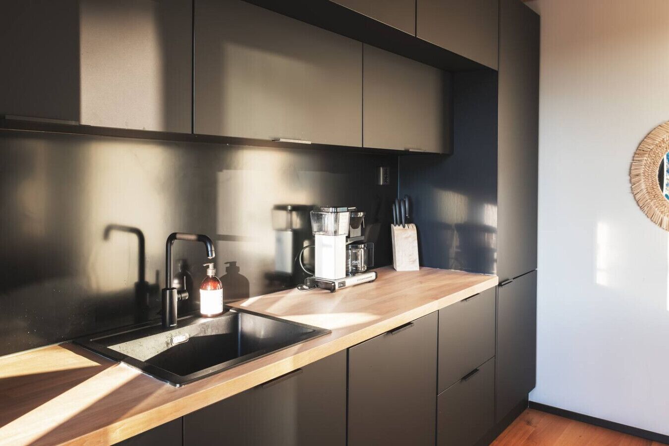 A modern kitchen with a built-in sink, a coffee maker, and a knife block on the countertop.