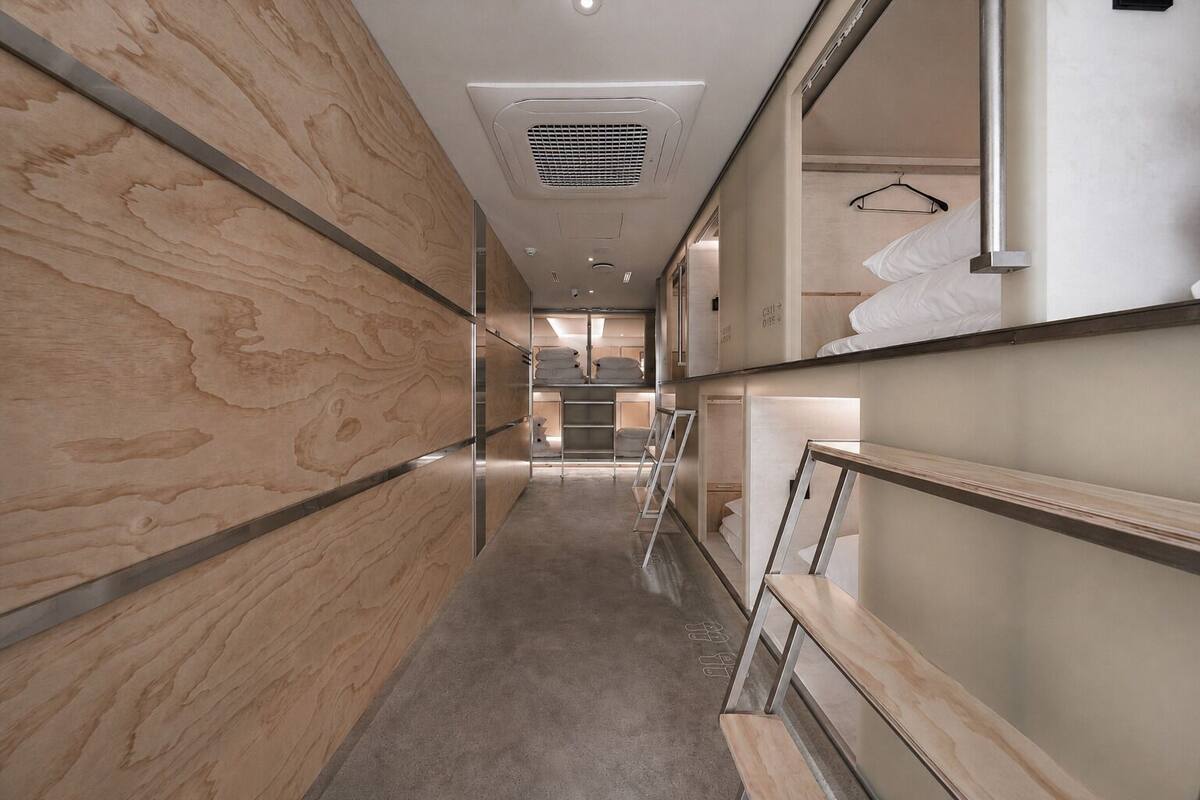 A corridor with wooden panel walls, a metal railing, and a bed with white bedding.