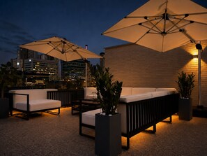 An outdoor seating area with umbrellas, a sofa, and potted plants.