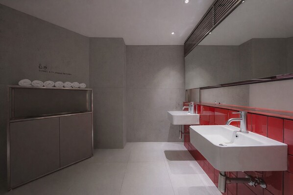 A modern bathroom with a grey wall, a towel rack, and two sinks with red accents. - Hotel at gangnam seoul (Seoul)