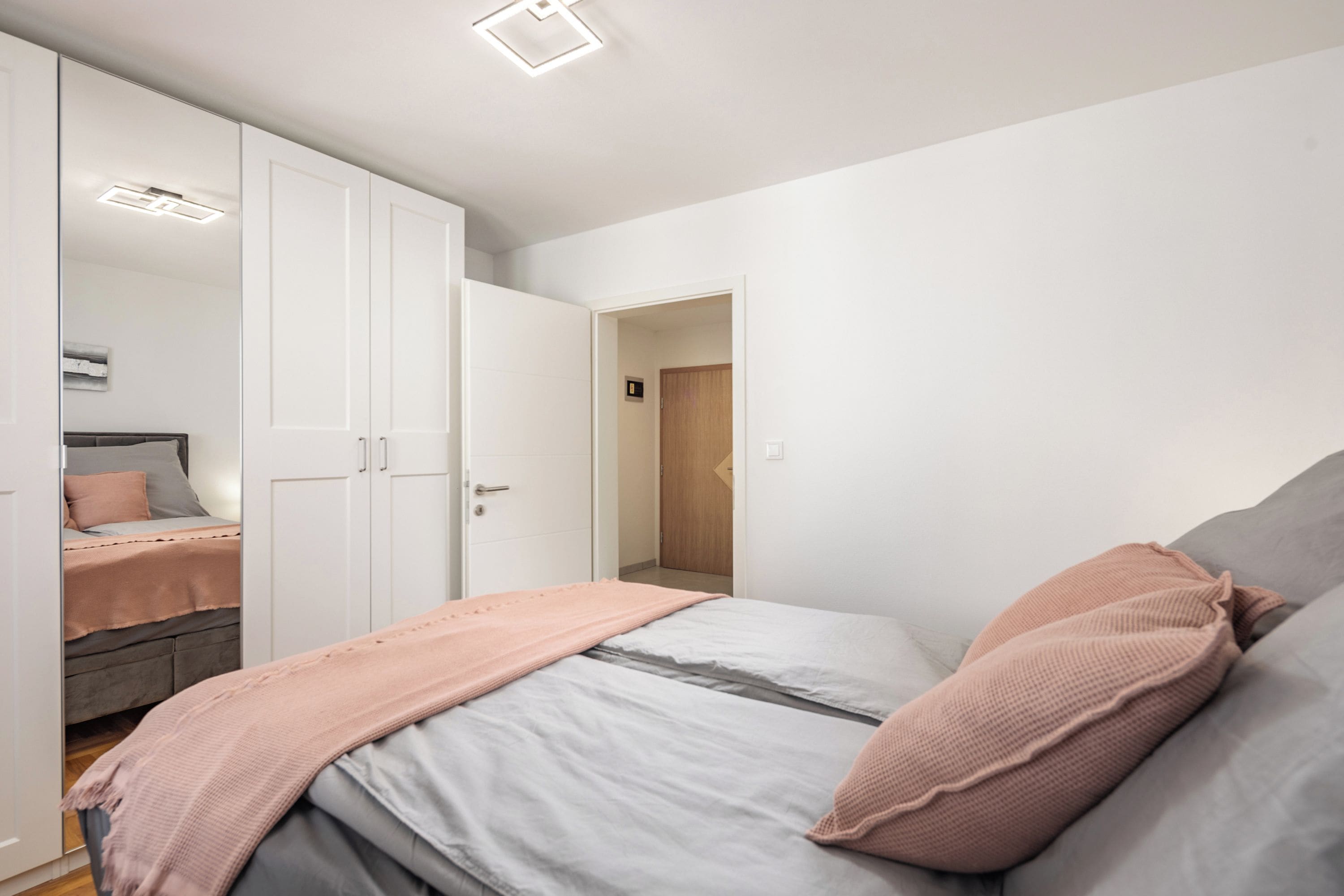 Ein Schlafzimmer mit einem Bett, einem Kleiderschrank und einer Tür zu einem anderen Raum.