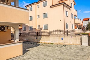 Un cortile lastricato con recinzione in metallo, una fontana e un edificio con diverse finestre.