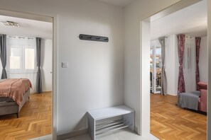 A modern room with a bed, a white bench, a coat rack, and a view of an outdoor balcony. - Apt Ana Walk To Beach /w Balcony (Medulin)