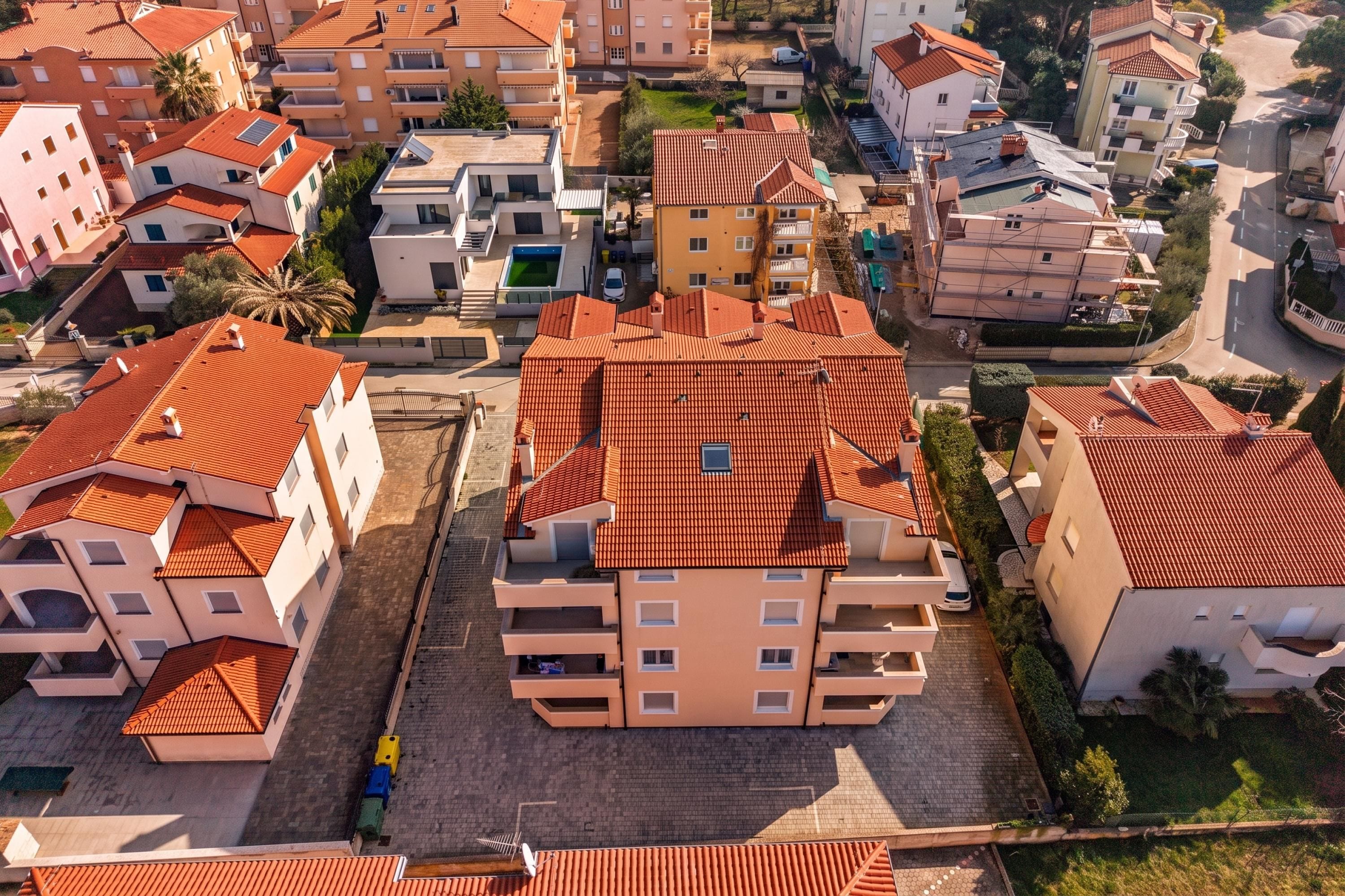 A residential area with multiple buildings, some with red-tiled roofs and others with white walls.