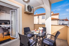 Un balcone con un tavolo da pranzo, sedie e una ventola.
