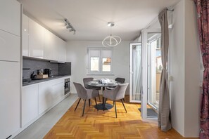 Una cucina moderna con mobili bianchi, un piano di lavoro nero e una zona pranzo con un tavolo rotondo e quattro sedie.
