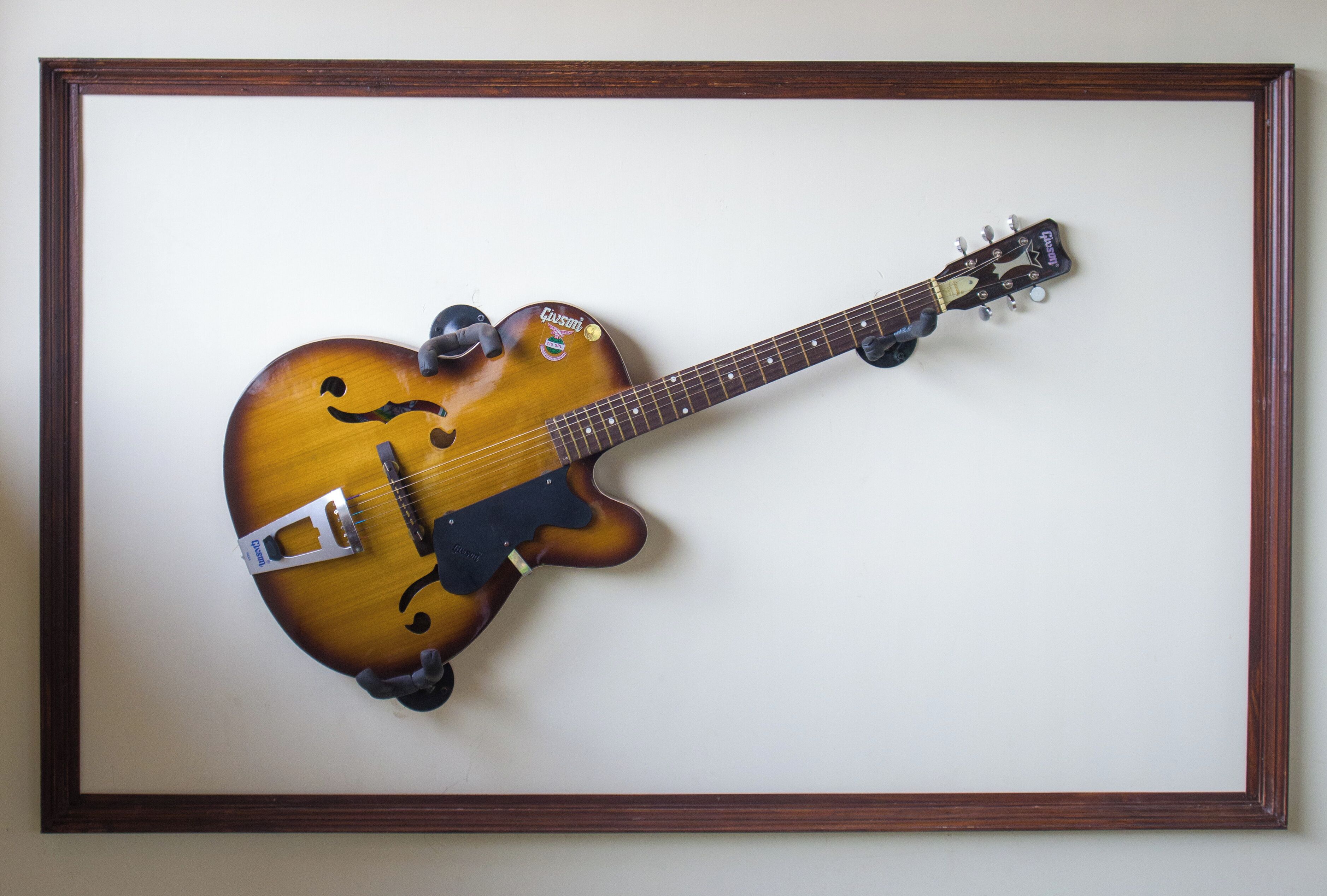 Una guitarra enmarcada con acabado sunburst, una cubierta antiparras y una correa.