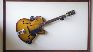 Una guitarra enmarcada con acabado sunburst, una cubierta antiparras y una correa.