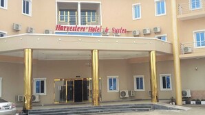 A hotel with a covered entrance, multiple windows, and air conditioning units. - Harvesters' Hotel And Suites  (Owerri)