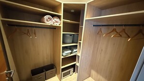 Vaatehuone, jossa on puuhyllyjä, vaatetanko ja mikroaaltouuni.